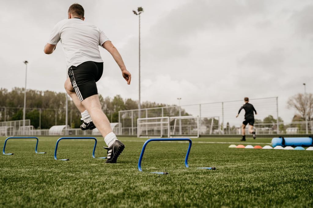 Athlete training on a field with blue hurdles